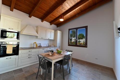 een keuken met witte kasten en een tafel met stoelen bij Boara Resort in Mottola