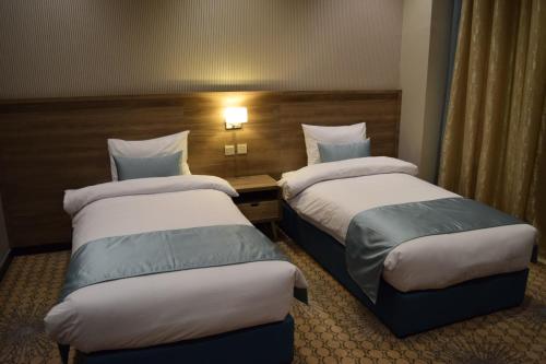 a hotel room with two beds and a desk at Glamour Inn AL Nuzha -جلامور ان النزهة in Jeddah