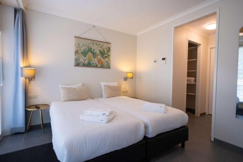 a bedroom with a white bed with towels on it at Flonk Hotel Groningen Centre, BW Signature Collection in Groningen