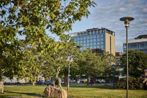 uma estátua de um dinossauro numa rocha num parque em Radisson Blu Caledonien Hotel, Kristiansand em Kristiansand