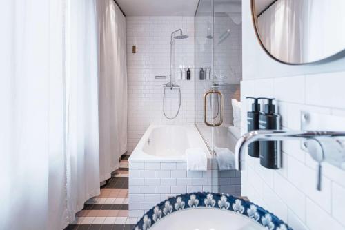 a bathroom with a tub and a shower and a sink at Story Hotel Riddargatan, part of JdV by Hyatt in Stockholm