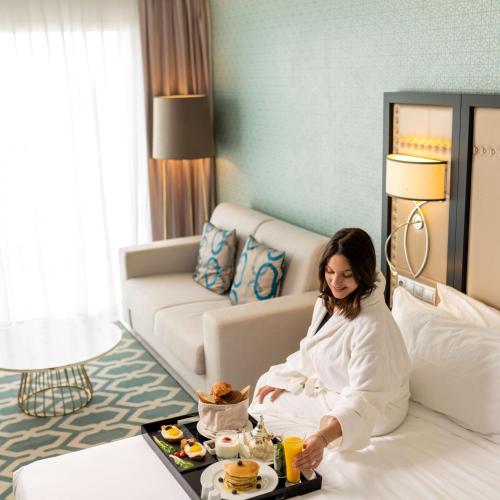 a woman sitting on a bed in a hotel room at Radisson Blu Resort Saidia Beach in Saidia 