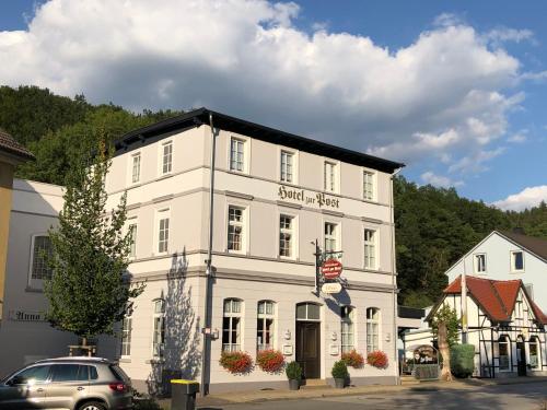 un edificio blanco con un coche aparcado delante de él en Hotel zur Post en Schalksmühle
