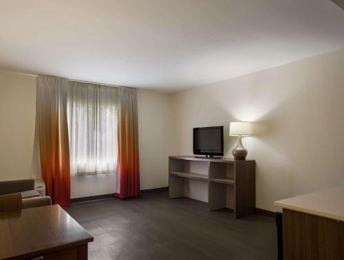 a hotel room with a television and a desk with a lamp at MainStay Suites Savannah Midtown in Savannah