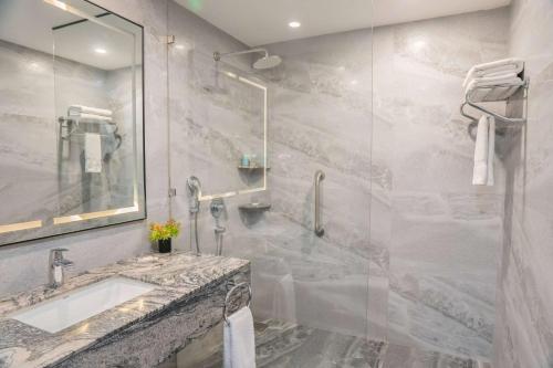 a bathroom with a sink and a glass shower at Ramada by Wyndham Murree Lower Topa Resort in Murree