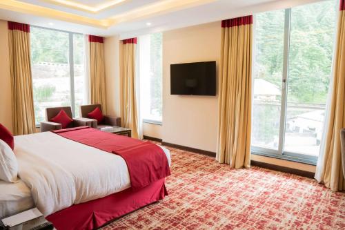 a hotel room with a bed and a large window at Ramada by Wyndham Murree Lower Topa Resort in Murree