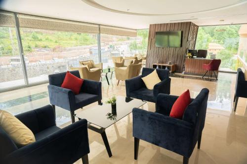 a living room with chairs and a tv and a table at Ramada by Wyndham Murree Lower Topa Resort in Murree