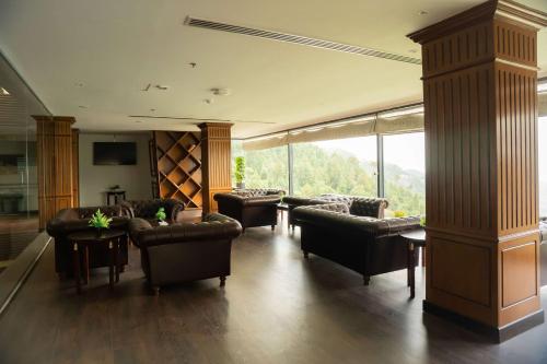 a large living room with couches and chairs and windows at Ramada by Wyndham Murree Lower Topa Resort in Murree