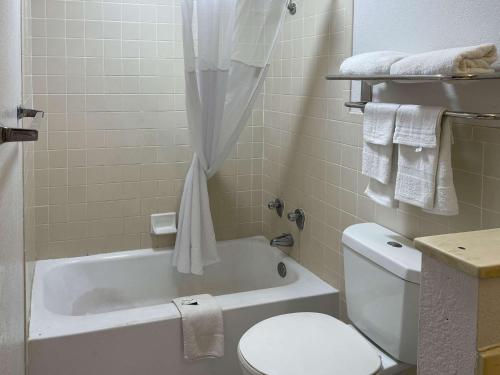 a bathroom with a white tub and a toilet and a sink at Motel 6 Opelika AL in Opelika