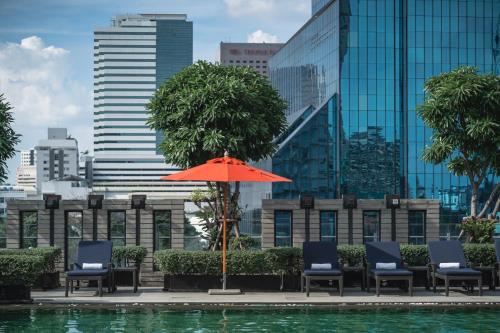 a pool with chairs and an umbrella in front of a city at Sathorn Vista, Bangkok - Marriott Executive Apartments in Bangkok