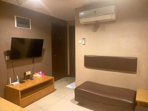 Una sala de estar con un sofá y un televisor de pantalla plana. en Two Bedroom Apartment at el Royale Hotel, en Bandung