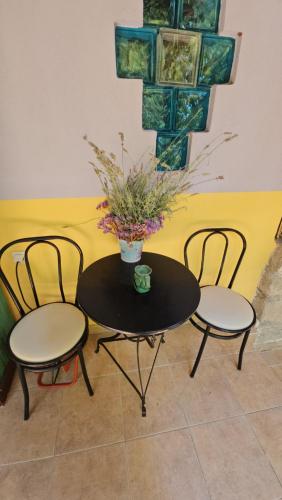 una mesa con dos sillas y un jarrón con flores en Home & Gardens 2-Bed Villa in Sevasti Katerini en Kateríni