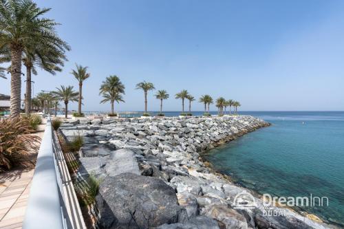 a rocky shore with palm trees and the ocean at Dream Inn - Address Beach Residence Fujairah - Premium Apartments in Fujairah