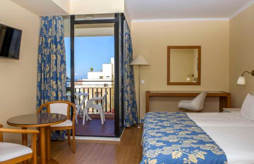 a hotel room with a bed and a table and a balcony at Dorisol Mimosa Studio Hotel in Funchal