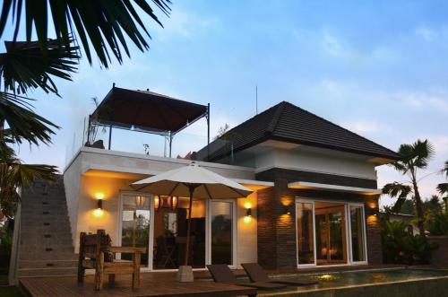 a small house with an umbrella and some chairs at The Samara Villas & Restaurant in Ubud