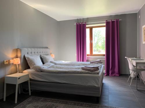 Schlafzimmer mit einem Bett mit lila Vorhängen und einem Fenster in der Unterkunft Tornedalens B&B in Övertorneå