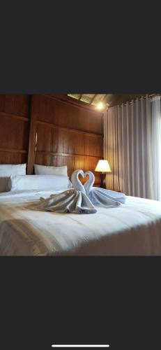 a bedroom with a bed with white sheets and a swan towel at Munduk Luwih Villa in Tabanan