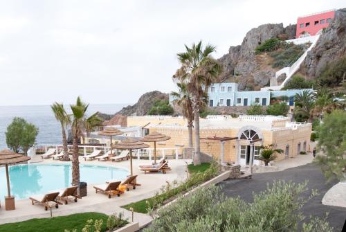 Kalypso Cretan Village Resort & Spa في بلاكاس: منتجع فيه مسبح والنخيل والمحيط