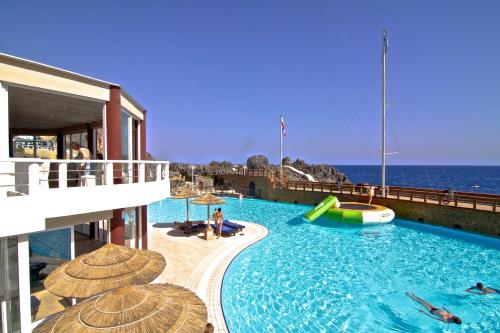 ein Pool mit Sonnenschirmen am Meer in der Unterkunft Kalypso Cretan Village Resort & Spa in Plakias