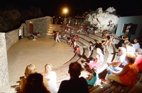 a group of people sitting on benches in a theatre at Kalypso Cretan Village Resort & Spa in Plakias