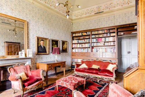 a living room with a couch and a table and books at Castello di Coazzolo in Neive