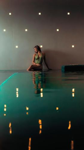 a woman sitting on the floor next to a pool of water at Habita79 Hotel Pompeii - MGallery Collection in Pompei