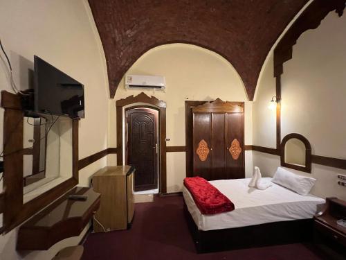 Elphardous Oasis Hotel في الأقصر: غرفة نوم بسرير وتلفزيون في غرفة