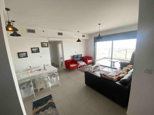 ein Wohnzimmer mit einem schwarzen Sofa und roten Stühlen in der Unterkunft דירת גג ים עכו חיפה נוף מרהיב in Akkon