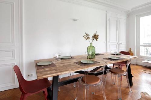 - une table à manger avec des chaises et un vase fleuri dans l'établissement Sweet Luxury Home Arc the Triomphe near Champs Elysées and Palais des Congrès 8 ppl, à Paris