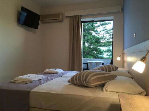 a hotel room with two beds and a window at Apollon Hotel in Sitia