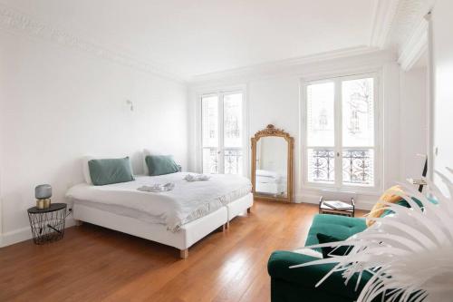 Magnificent apt in Paris near Champs Elysées-8 ppl في باريس: غرفة نوم بيضاء بسرير واريكة خضراء