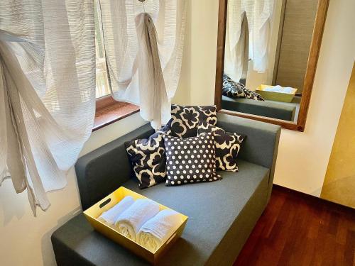 Habitación con sofá con almohadas y ventana. en Alloggio Marta Malpensa Milano-Laghi en Busto Arsizio