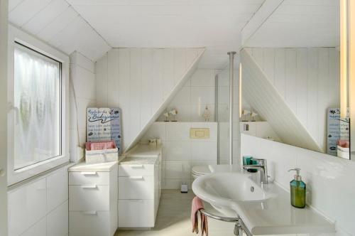 a white bathroom with a sink and a staircase at Fewo am Deich in Wilhelmshaven