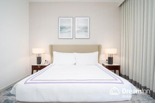 a bedroom with a large white bed with two lamps at Dream Inn - Address Beach Residence Fujairah - Premium Apartments in Fujairah