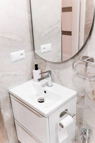 a white bathroom with a sink and a mirror at Apartament Pastel Room in Leśna