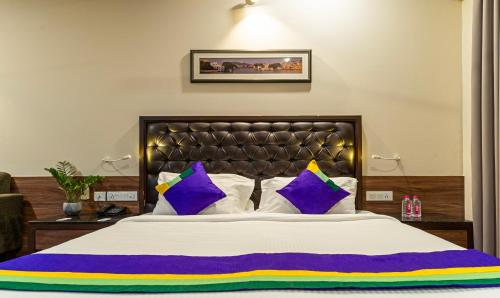 um quarto com uma cama grande com almofadas roxas e amarelas em Treebo Tryst Baramasi By Jai Club Prime em Jaipur