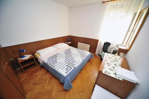 a small bedroom with a bed and a table at Rooms Novaković in Opatija