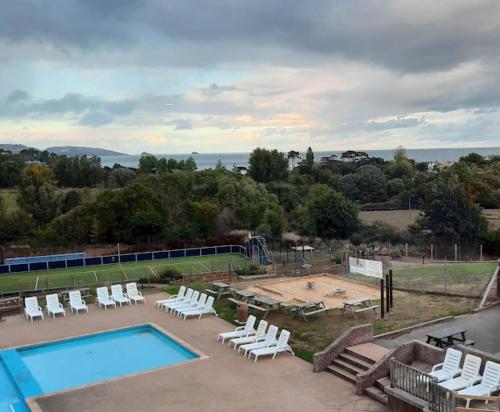 a swimming pool with lounge chairs and a tennis court at A5 Avocet Rise in Paignton