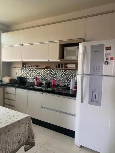 een keuken met een witte koelkast en een magnetron bij Apartamento Day in Cuiabá