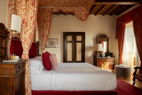 a bedroom with a large white bed with red curtains at Loggiato Dei Serviti in Florence