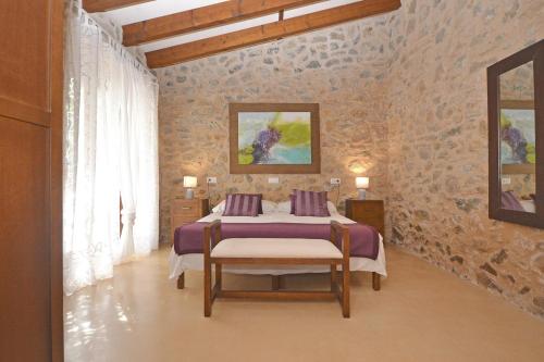 Un dormitorio con una cama en una pared de piedra. en Es Romegueral, en Artà