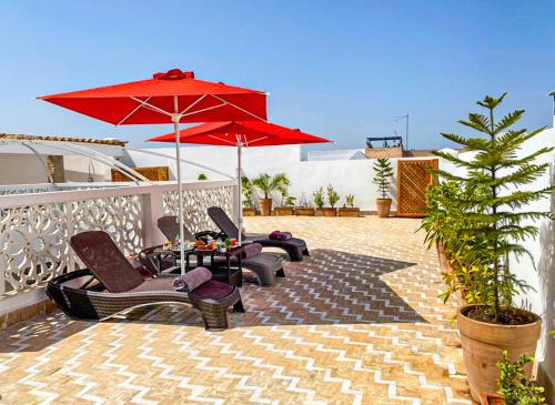 un gruppo di sedie e un ombrellone su un patio di Riad El Pacha a Rabat