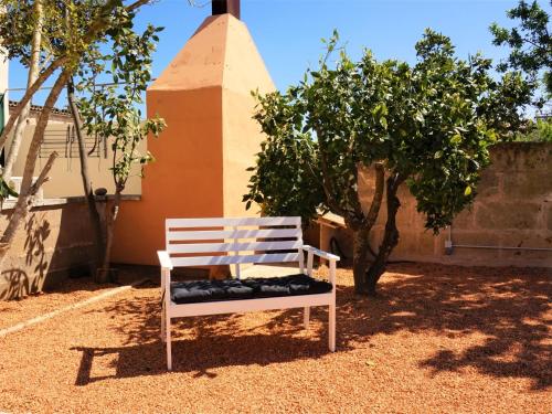 a white bench sitting on the ground next to a tree at Ca sa comare in Llucmajor
