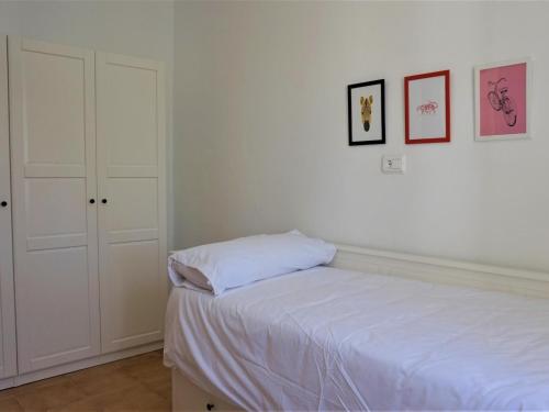 a white bedroom with a bed and some pictures on the wall at Ca sa comare in Llucmajor