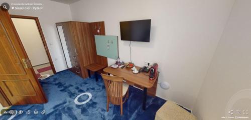 a room with a desk and a tv on a wall at Hotel Selsky Dvur in Vyškov