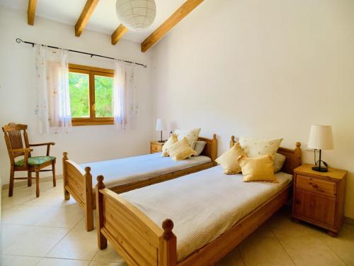 2 łóżka w pokoju z krzesłem i oknem w obiekcie Casa Dorotea w mieście Son Serra de Marina