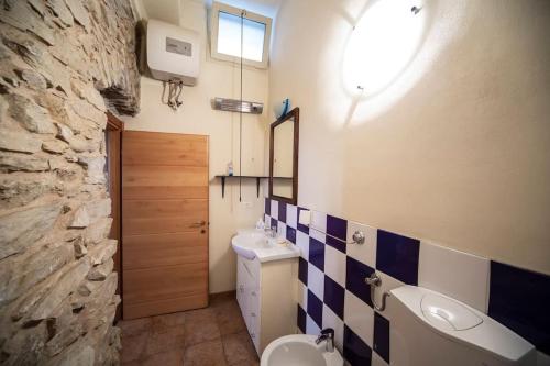 a bathroom with a sink toilet and a stone wall at Ginestra in Cipressa