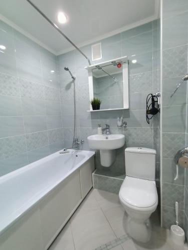 a bathroom with a toilet and a sink and a bath tub at Квартира с гостиничным сервисом в центре Петропавловска in Petropavlovsk