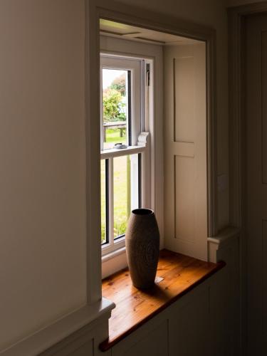 a vase sitting on a wooden floor in front of a window at Rosecott in St Ives