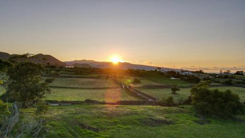 a sunset over a field with the sun in the background at Quinta da Paz Azores in Pico da Pedra
